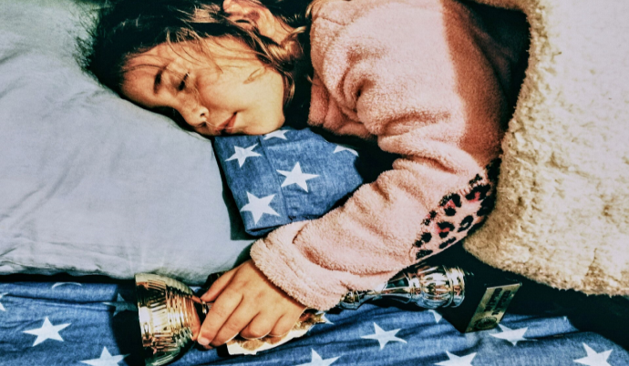 Looking down on a young girl in bed holding a trophy