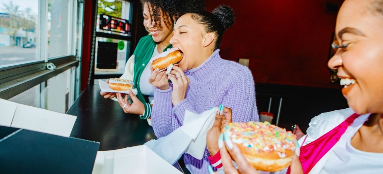 Young women enjoy a dessert, sporting colorful street style fashion at their lunch break