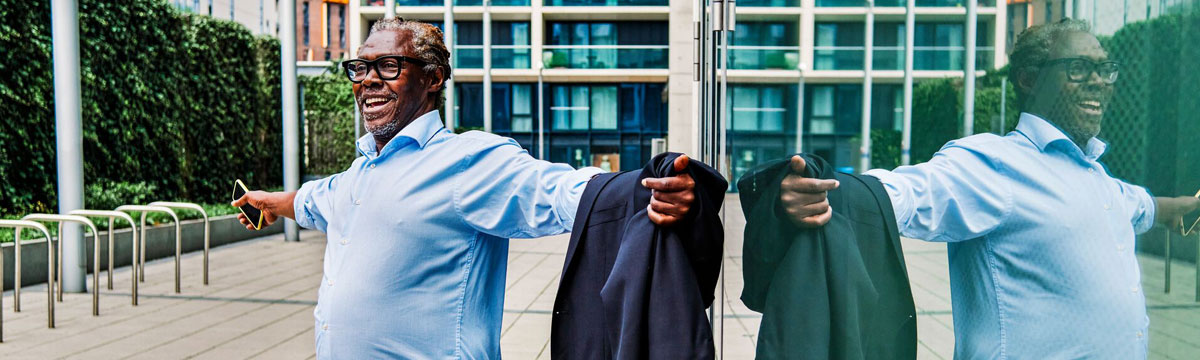 Mature businessman stretching out his arms in front of a glass building