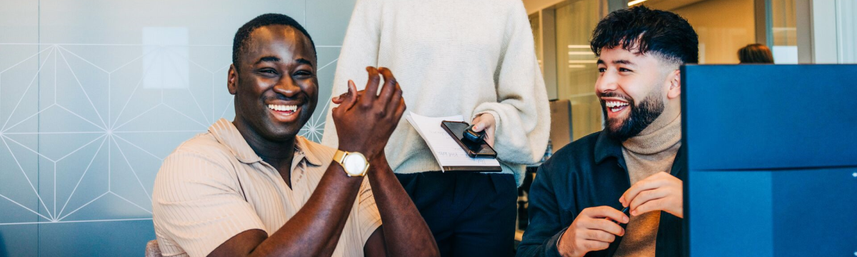 Three happy working colleagues laughing at their desk