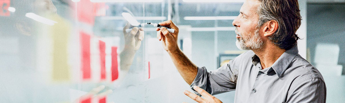 Man takes notes on a glass whiteboard in the office