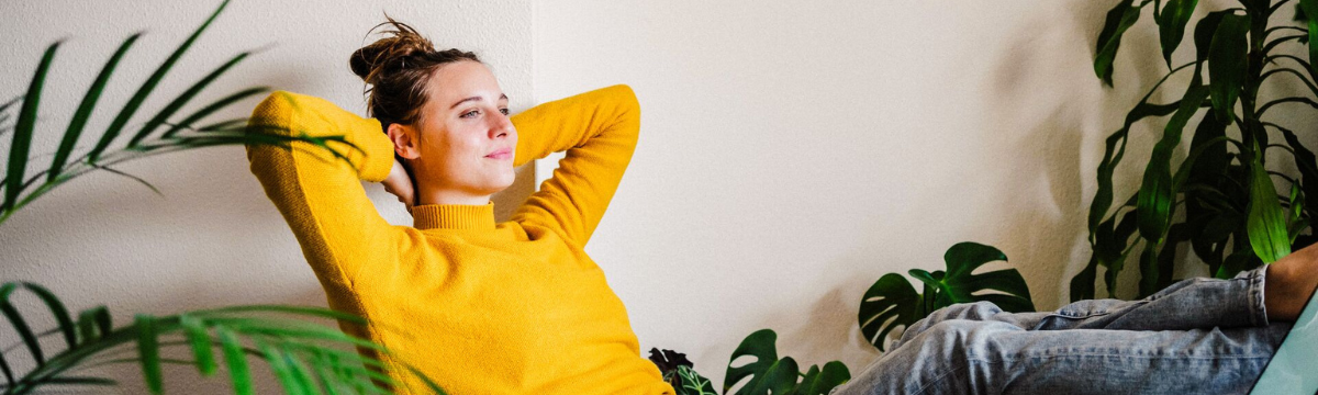 Young woman in yellow sweater reclining at her desk