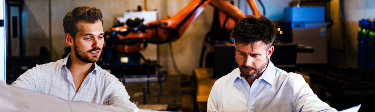 Two male colleagues looking at some plans in a factory